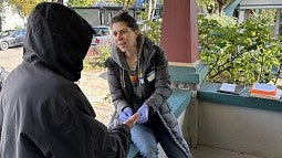 Professor Jo Weaver sitting on a porch talking to someone